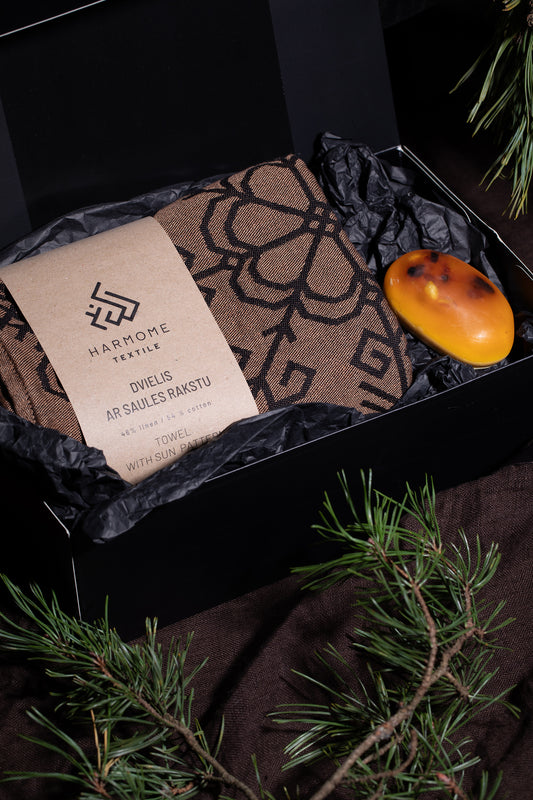 Dāvanu komplekts ar dvieli ar Saules rakstu un ziepēm ar dzintara gabaliņiem, skaisti iepakotas kastē no HarmoMe.