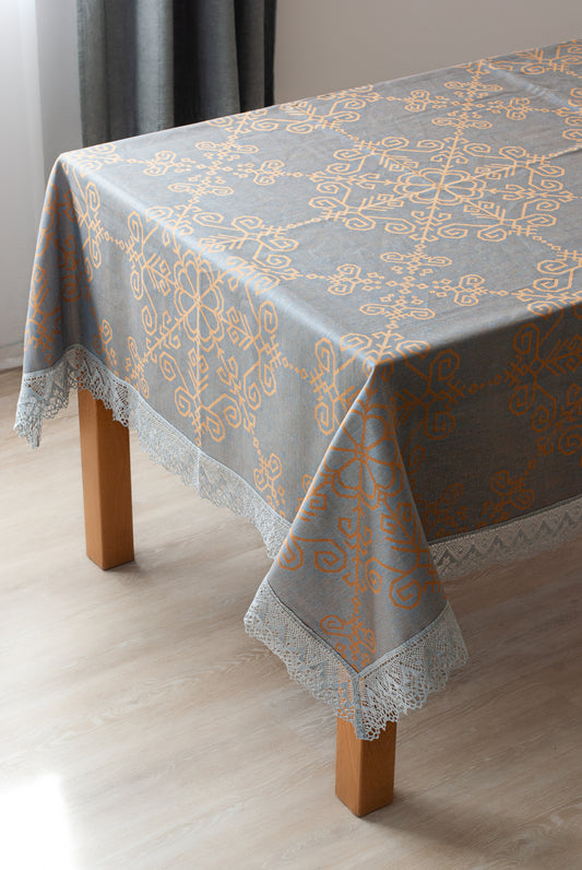 Lina galdauts ar mežģīni un Saules rakstu, uzklāts uz galda, labi redzama platā mežģīne no HarmoMe.