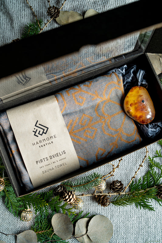 Dāvanu komplekts ar pelēku lina dvieli un ziepēm ar dzintara gabaliņiem, skaisti iepakoti kastē no HarmoMe.